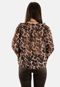 Blusa a maniche lunghe realizzata in un tessuto leggero e trasparente, caratterizzata da una stampa leopardata beige e nera e leggere spalle a palloncino.
