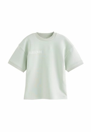 Lichtgroen oversized t-shirt van zachte katoen, met korte mouwen en witte tekst die "SUBSCRIBE" op de voorkant en zijkant zegt.