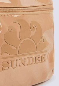 Zaino beige lucido Sundek con design in rilievo a forma di sole e logo del marchio, dotato di chiusura con zip e texture liscia.