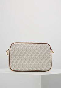 Prostokątna beżowa torebka na ramię z brązowymi wykończeniami, złotą łańcuchową rączką oraz powtarzającym się wzorem logo "MK" na białej powierzchni.