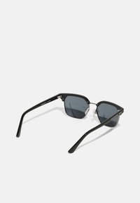 Ochelari de soare negri cu o ramă geometrică, lentile gri polarizate, accente metalice și suporturi pentru nas transparente; finisaj neted și design elegant.
