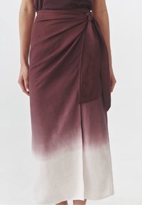 Rode ombre wikkelrok met een geknoopt strikdetail, die overgaat in een lichtere tint aan de zoom, gemaakt van een zachte, gestructureerde stof.