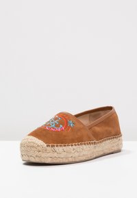 Brune ruskindsespadrille med broderet blomsterdesign. Såle af jute-reb, rund tå og lavprofil slip-on stil.