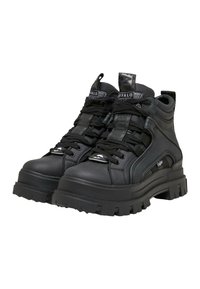 Zwarte chunky plateau enkellaarsjes met dikke rubberen zolen, veters aan de voorkant en merklabels en trekhaakjes.