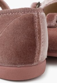 Samt Schuhe in zartem Rosa mit strukturierter Oberfläche, ausgestattet mit einer soliden Gummisohle und gestickten Akzenten. Die Rückansicht betont die gepolsterte Ferse.