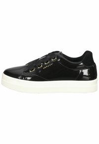 Zapatillas de charol negras con suela de goma blanca, con cordones de tela negra y ojales dorados. Diseño minimalista con detalle de logo.