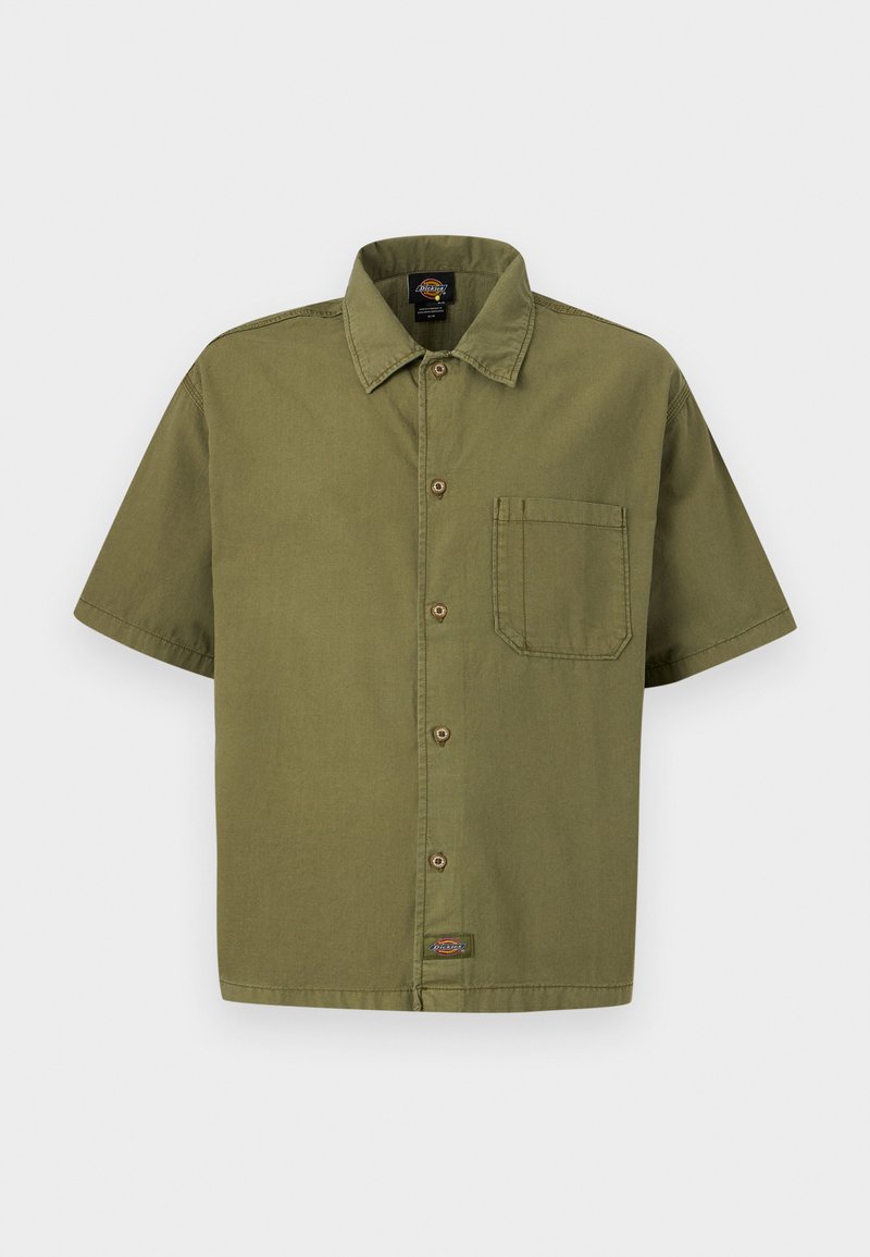 Camisa de manga corta en verde oliva con botones, bolsillo en el pecho y cuello, mostrada extendida sobre un fondo claro.
