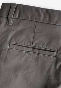 Dark gray trousers with a smooth, textured fabric; features a back pocket with a stitching detail.