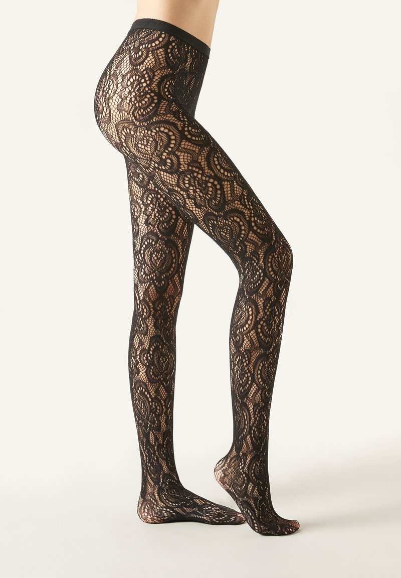 Pantys de encaje negro con un intrincado patrón floral, una textura transparente y una cinturilla sólida. El diseño ofrece una silueta ceñida.