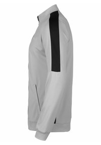 Giacca grigia con accenti neri sui lati, colletto rialzato, chiusura con zip e tasche laterali. Realizzata in un materiale leggero e liscio.