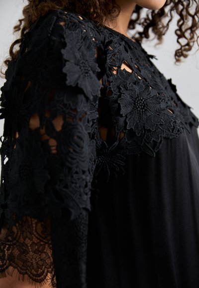 Μαύρο φόρεμα με λουλούδια δαντέλας στα μανίκια, με υφή κεντήματος και ρέουσα σιλουέτα.