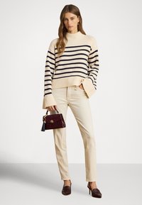 Beige genser med striper i marineblått, kremfargede bukser og en vinrød veske. Hælene har en rundet design; vesken har en dusk som dekorasjon.