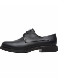 Chaussure habillée en cuir noir avec une texture lisse, bout arrondi, design à lacets et une semelle en caoutchouc robuste et basse.