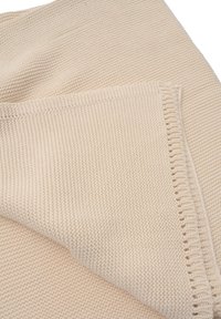 Beige gestrickte Decke mit einer strukturierten Oberfläche, die an einer Kante einen dekorativen Fransenbesatz hat. Weicher Stoff, leichtes Design.