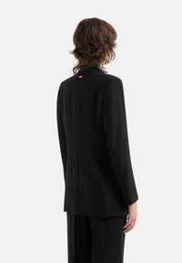 Blazer nero con maniche lunghe, design strutturato, texture liscia e dettaglio di spacco posteriore. Linee semplici e pulite senza embellishments.