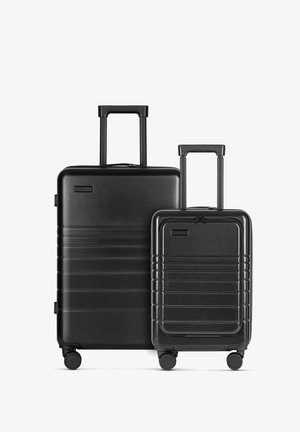 Zwei schwarze Hartschalenkoffer, einer größer mit einem Teleskopgriff und Rollen, der andere kleiner, beide mit geripptem Design und Reißverschlüssen.