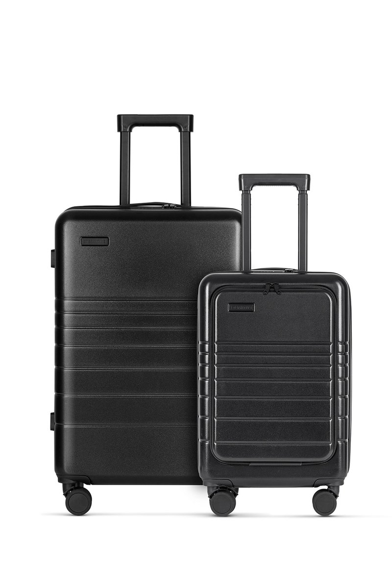 Two black hard-shell suitcases, one larger with a telescopic handle and wheels, the other smaller, both featuring ribbed designs and zippers.