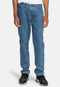 Lichtblauwe spijkerbroek met een rechte pijp, vijf-pocket stijl en subtiele vervaging, gecombineerd met zwarte sportschoenen.