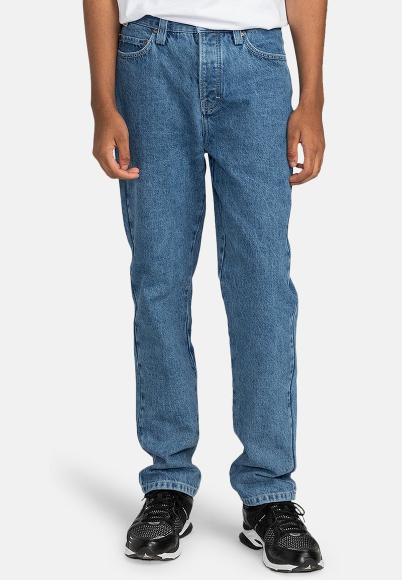 Lichtblauwe spijkerbroek met een rechte pijp, vijf-pocket stijl en subtiele vervaging, gecombineerd met zwarte sportschoenen.