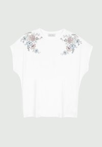 T-shirt en coton blanc avec des manches courtes et larges, ornée de broderies florales en rose, bleu et vert sur les épaules. Texture douce.