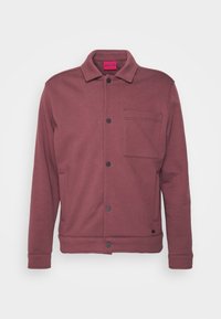 Mörkröd jacka i mjukt tyg, med krage, framknäppning med knappar, en bröstficka och sidfickor, med svarta knappar.