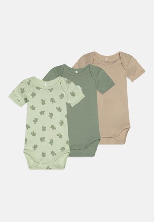 Três bodies de bebé de manga curta: verde-claro com padrão de tartaruga, verde-escuro sólido e bege sólido. Feitos de algodão macio.