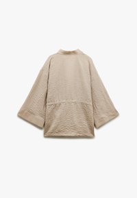 Vaaleanbeige, teksturoitu kimono-tyylinen paita, jossa on pystykaulus ja leveät hihat. Ominaisuuksiin kuuluu rypistynyt kangas ja väljä, rento istuvuus.
