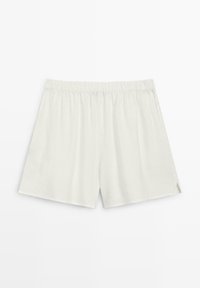 Weiße Shorts mit elastischem Bund, locker geschnitten und mit kleinen seitlichen Schlitzen, flach auf weißem Hintergrund liegend dargestellt.