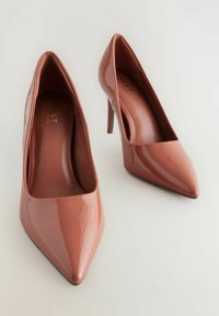 Zapatos de tacón alto y punta afilada, de color rosa suave y brillo. Textura suave con un diseño elegante y contemporáneo, y con un mínimo de detalles.