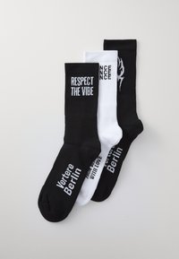 Three pairs of socks: black with white text "RESPECT THE VIBE," white with black text, and black with white logo, cotton blend, mid-calf length.