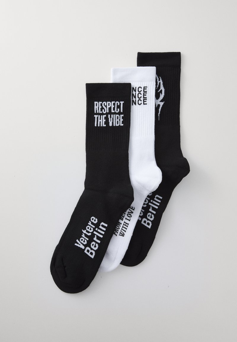 Três pares de meias: uma preta com texto branco "RESPECT THE VIBE", uma branca com texto preto, e uma preta com logo branco, em mistura de algodão, comprimento até o meio da panturrilha.