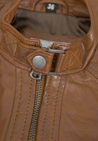 Brown leather jacket with a visible zipper, snap closure, and quilted accents on the collar. Tag shows size 36. Smooth texture.