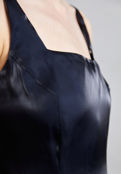 Zwarte satijnen jurk met vierkante decolleté en dunne bandjes, met eengladde textuur en een subtiele glans.