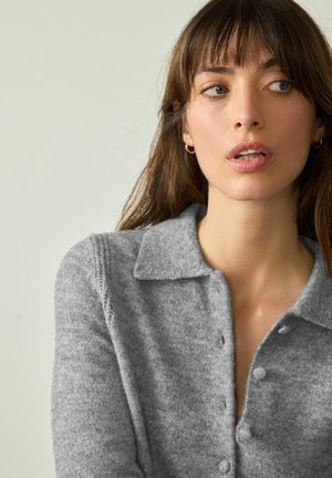 Gray knit cardigan with a collared neckline, button front, and textured fabric. Featuring a soft finish and visible stitching details.