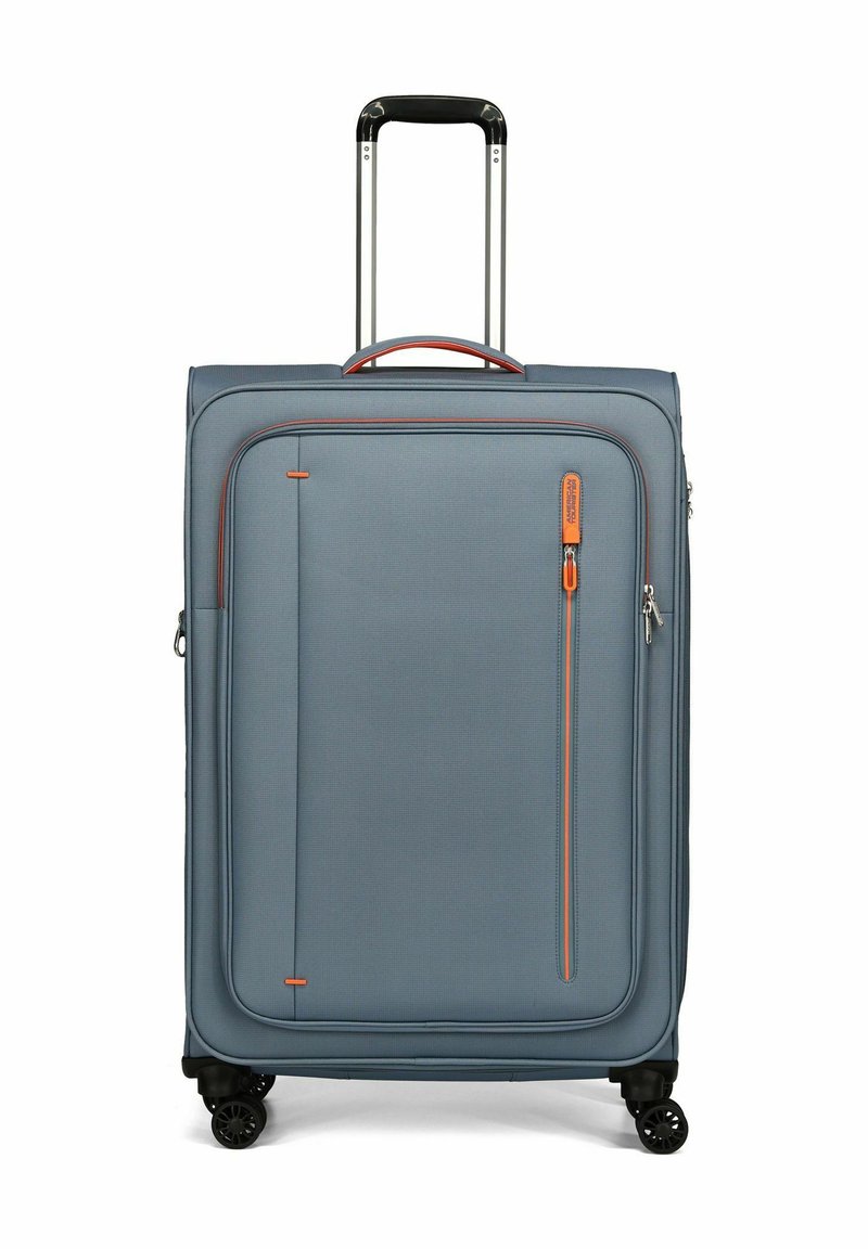 Valigia soft-shell blu con tasca frontale con zipper, dettagli arancioni, maniglia ergonomica e quattro ruote nere per una facile mobilità.