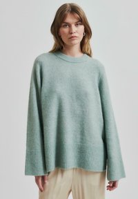 Mentolově zelený oversized svetr ve měkk�é textuře s žebrovaným lemem a manžetami. Má kulatý výstřih a spadlá ramena pro ležérní střih.
