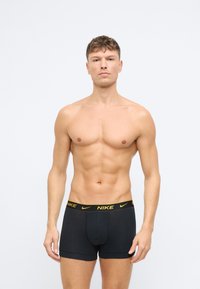 Čierne bavlnené boxerky s širokým zlatým pásom s logom Nike, s priliehavým strihom a hladkou textúrou.