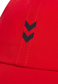 Rød kasket med en glat stoftekstur, der har sorte chevron-accenter og kontrasterende syninger, der fremhæver det sporty design.