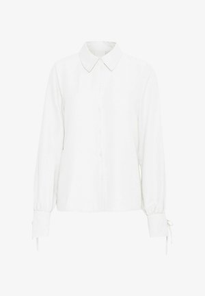 Valge pikade varrukatega pluus, millel on krae, nööpide ettepanek ja gathered cuffs, mis sisaldavad sidumisrihmasid. Tekstuuriga kangas, millel on kerge välimus.