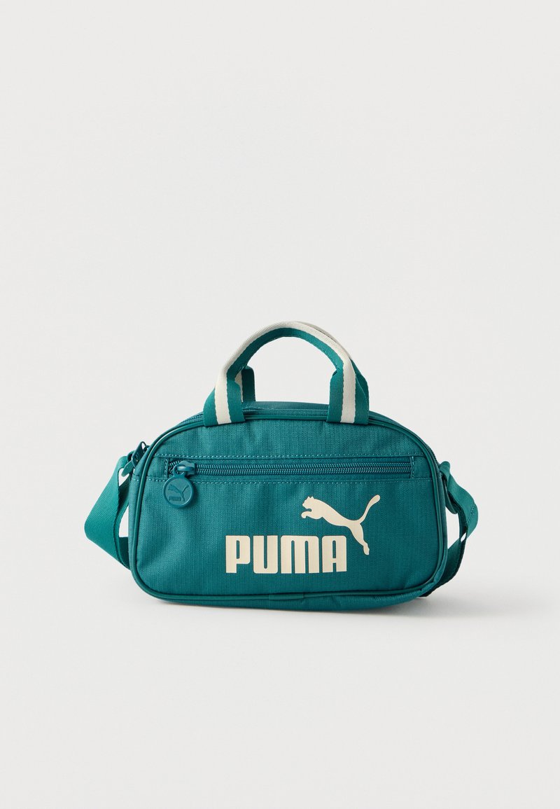 Τσαντάκι crossbody Teal Puma με τσέπη στο μπροστινό μέρος με φερμουάρ, λευκό λογότυπο και διπλές ριγωτές λαβές στην κορυφή, σε απλό λευκό φόντο.