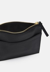 Zwarte leren portemonnee met een getextureerde afwerking, gouden ritssluiting en een extern zakje. Binnenkant van contrasterende donkere stof.