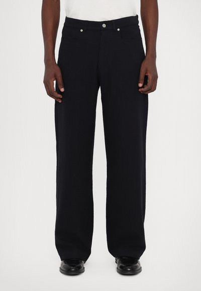 Pantalons larges bleu marine foncé en tissu texturé, dotés de poches avant, de quincaillerie en argent et d'une fermeture à bouton à la taille.