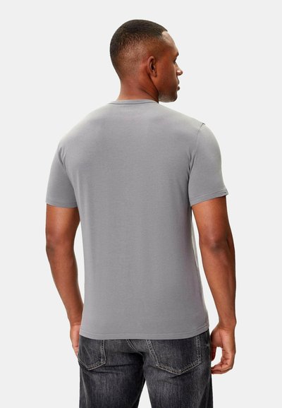 Harmaa lyhythihainen t-paita pehmeästä kankaasta, pyöreä kaula-aukkosuunnittelu, slim fit -malli, sileä pinta, yhdistetty tummiin farkkuihin, kuvattu takaa.