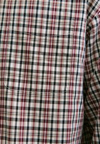Camicia a quadri nei toni bianco, nero e rosso; presenta un classico motivo a scacchi con una tasca sul petto e un tessuto testurizzato.