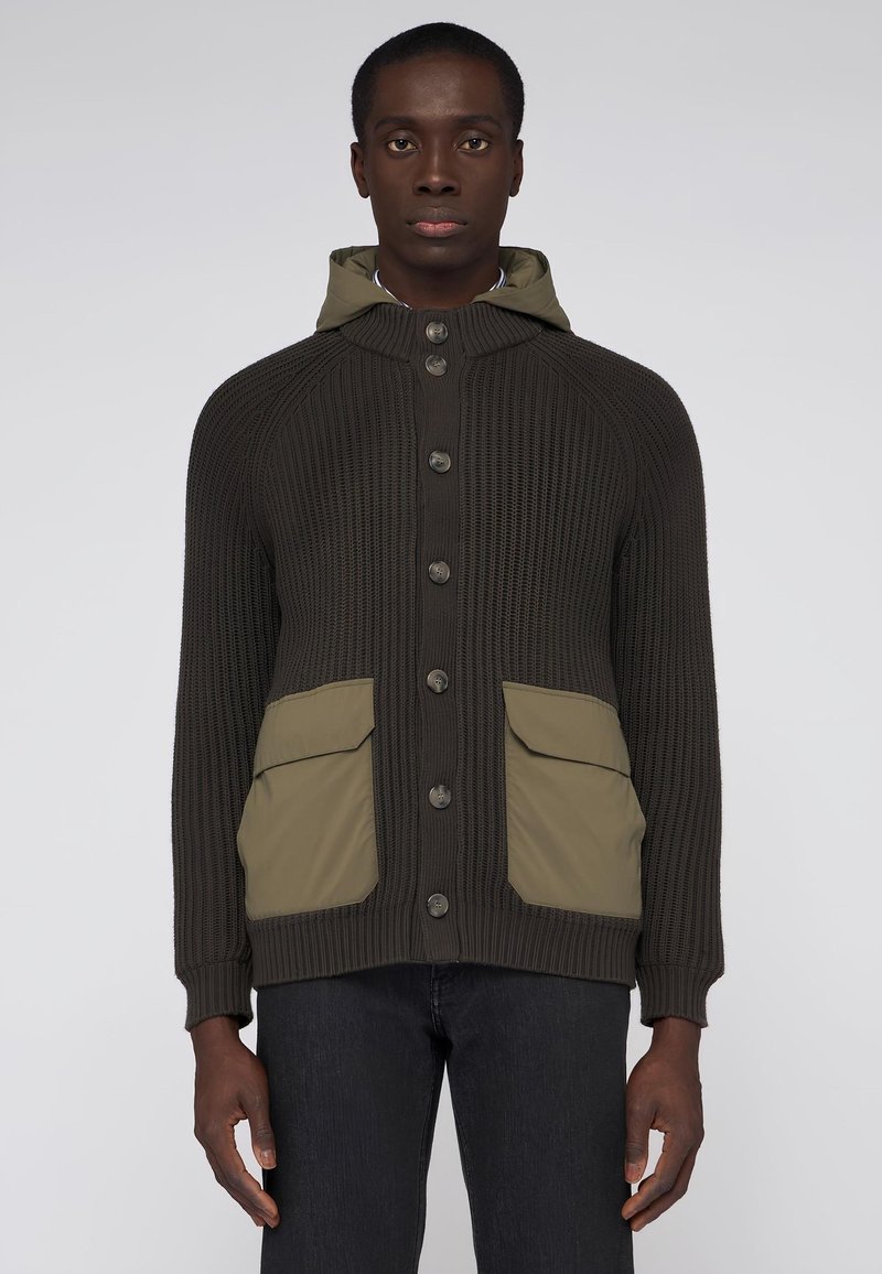 Mönstrad tröja i mörkbrun färg med knappslå framtill, huva och olivgröna fickdetaljer. Har ribbstruktur och raglanärmar.