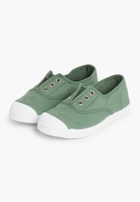 Des chaussures slip-on en toile verte avec des semelles en caoutchouc blanches, dotées d'œillets décoratifs et d'un bout arrondi. Design simple, texture lisse.