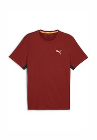 Camiseta roja de manga corta hecha de tejido texturizado, que presenta un logo blanco en el lado izquierdo del pecho y una etiqueta amarilla en el cuello. Detalles en negro en las mangas.