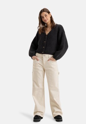 Black knitted cardigan with a V-neck and button closure, paired with beige cargo pants and black platform shoes. Plain background.