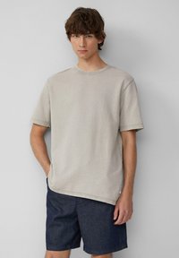 Jasnoszara bawełniana koszulka z krótkim rękawem i okrągłym dekoltem, w połączeniu z ciemnoniebieskimi denimowymi szortami. Prosty i luźny krój.