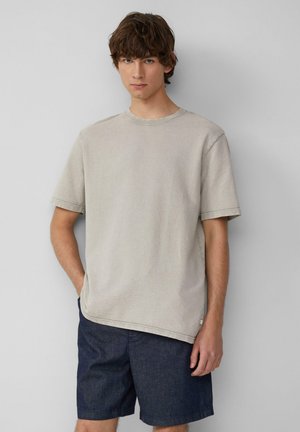T-shirt en coton gris clair à manches courtes et col rond, associé à un short en denim bleu foncé. Design simple et décontracté.